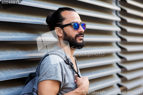 Image of man with backpack standing at city street wall