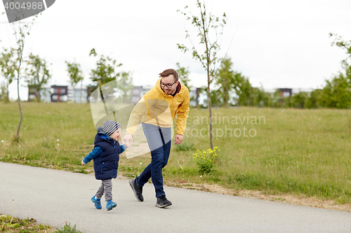 Image of happy father and little son walking outdoors