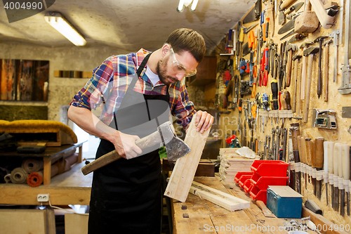 Image of carpenter with ax and board working at workshop