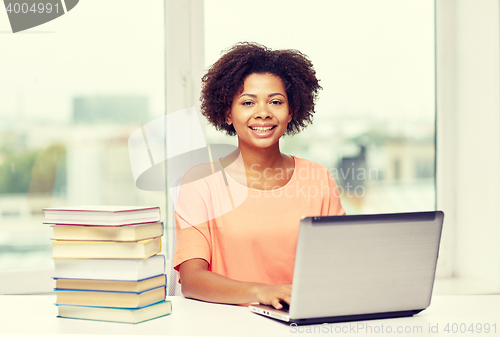 Image of happy african american woman with laptop at home