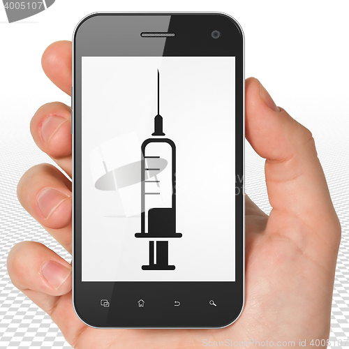 Image of Health concept: Hand Holding Smartphone with Syringe on display