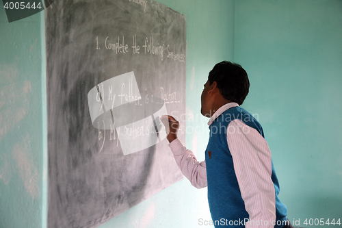 Image of Teacher writes on blackboard at school, Kumrokhali, West Bengal, India