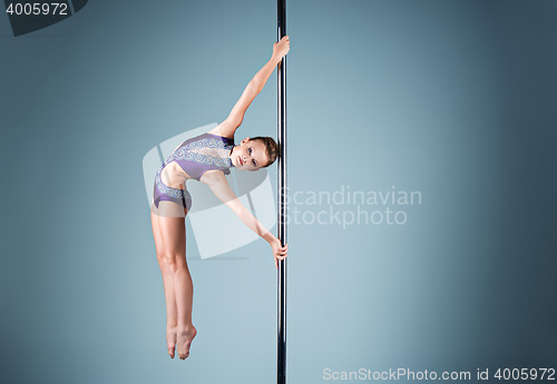 Image of The strong and graceful young girl performing acrobatic exercises on pylon
