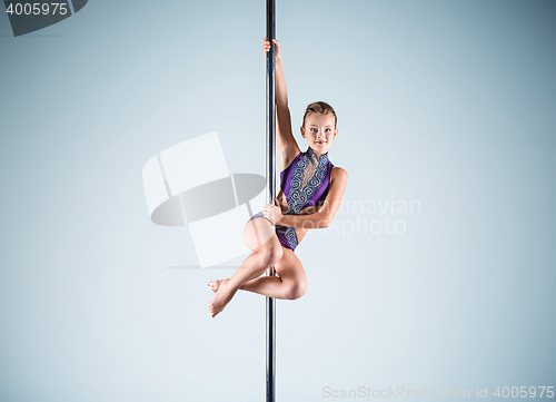 Image of The strong and graceful young girl performing acrobatic exercises on pylon