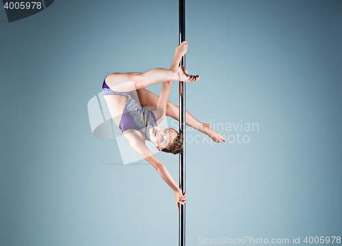 Image of The strong and graceful young girl performing acrobatic exercises on pylon