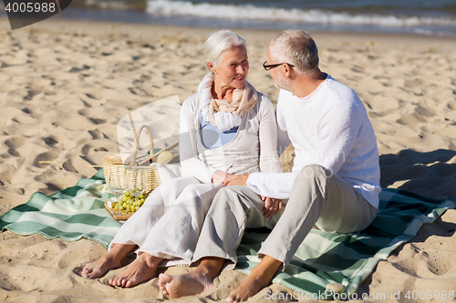 Image of happy senior couple having picnic on summer beach