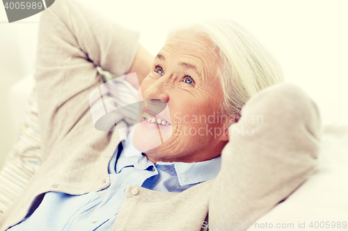 Image of happy senior woman resting on sofa at home