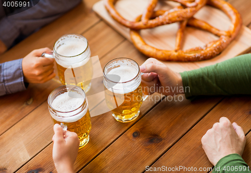 Image of close up of hands with beer mugs at bar or pub