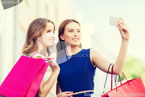 Image of happy women with shopping bags and smartphone