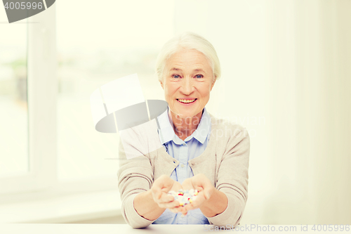 Image of happy senior woman with medicine at home