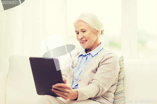 Image of happy senior woman with tablet pc at home