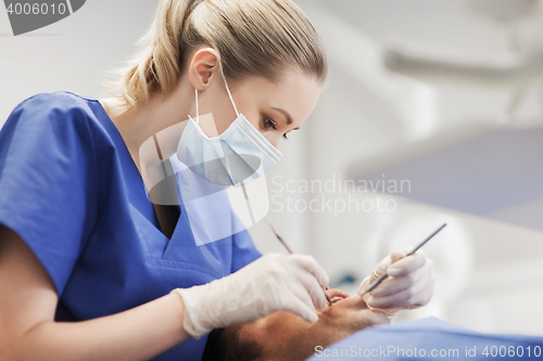 Image of female dentist checking up male patient teeth