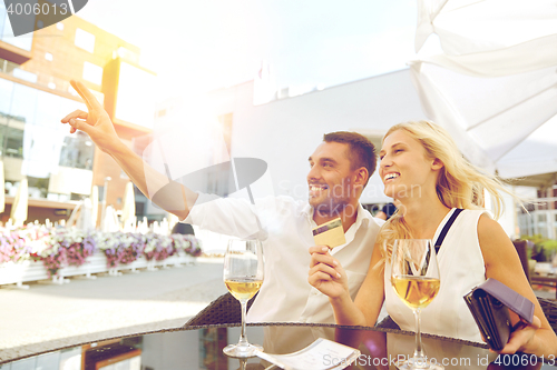 Image of happy couple with wallet paying bill at restaurant