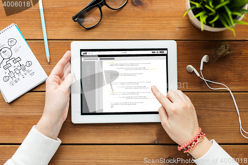 Image of close up of woman with tablet pc on wooden table