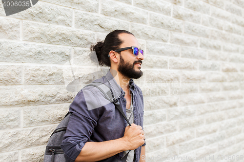 Image of man with backpack standing at city street wall