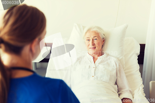 Image of doctor or nurse visiting senior woman at hospital