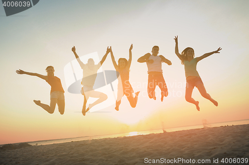 Image of smiling friends dancing and jumping on beach