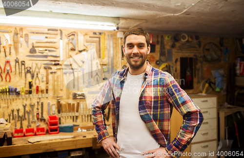 Image of happy young workman in checkered shirt at workshop