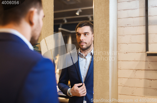 Image of man trying jacket on at mirror in clothing store