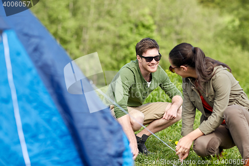 Image of happy couple setting up tent outdoors