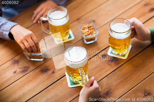 Image of close up of hands with beer mugs at bar or pub