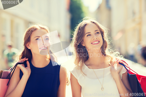 Image of happy women with shopping bags walking in city 