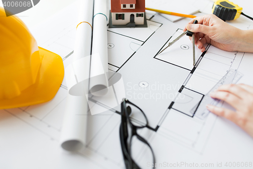 Image of close up of hands with compass measuring blueprint