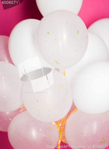 Image of close up of white helium balloons over pink