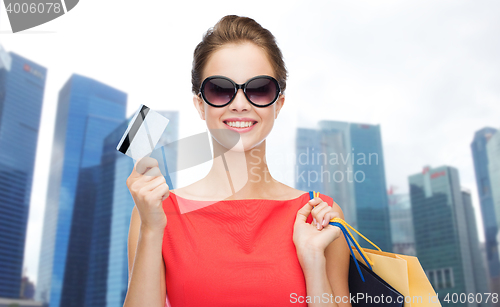 Image of woman with shopping bags and credit card over city