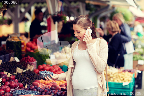 Image of pregnant woman calling on smartphone at market