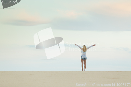 Image of Free woman enjoying freedom on beach at dusk.