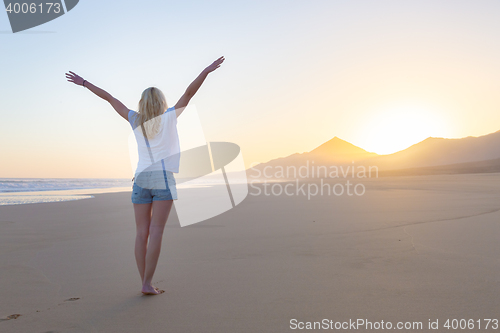 Image of Free woman enjoying freedom on beach at sunrise.