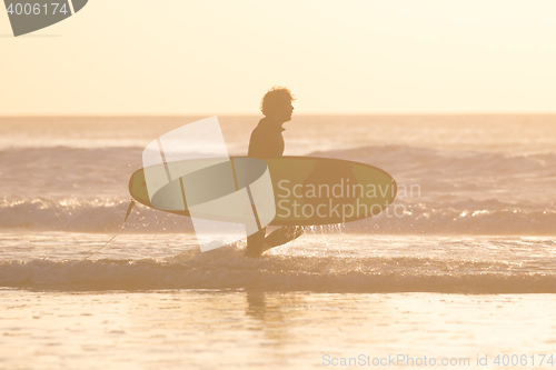 Image of Silhouette of surfer on beach with surfboard.