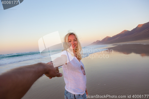 Image of Romantic couple holding hands on beach.