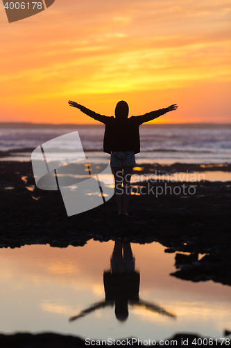 Image of Free woman enjoying freedom on beach at sunset.