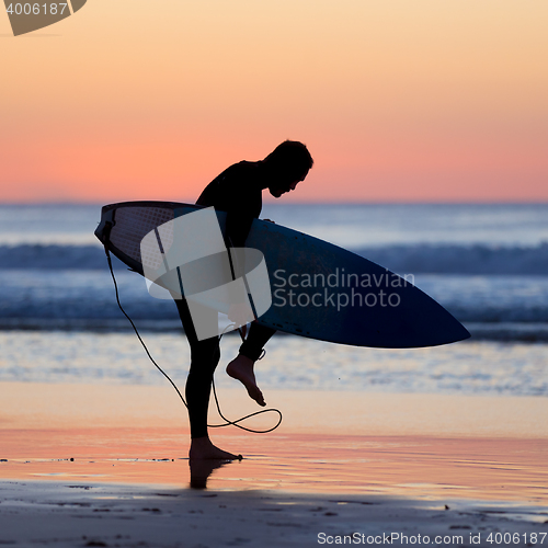 Image of Silhouette of surfer on beach with surfboard.