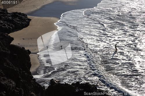 Image of Silhouette of man and dog having fun on seaside.