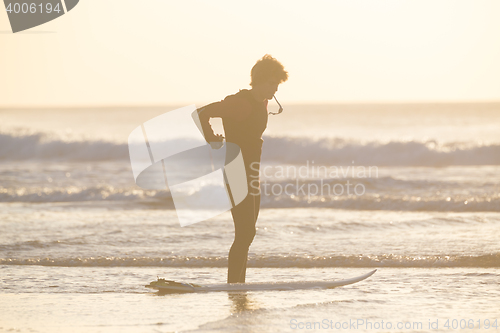 Image of Silhouette of surfer on beach with surfboard.