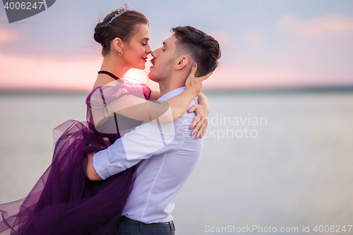 Image of Young romantic couple relaxing on the beach watching the sunset