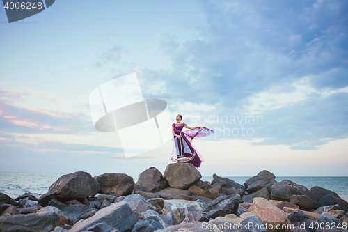 Image of Young romantic woman posing on the beach watching the sunset