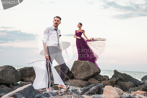 Image of Young romantic couple relaxing on the beach watching the sunset