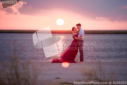 Image of Young romantic couple relaxing on the beach watching the sunset