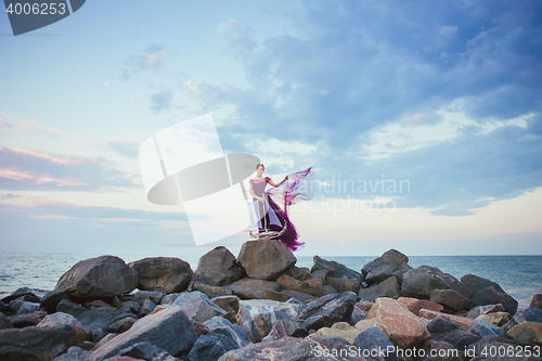 Image of Young romantic woman posing on the beach watching the sunset