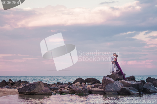 Image of Young romantic couple relaxing on the beach watching the sunset