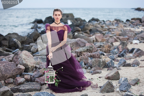 Image of Young romantic woman posing on the beach watching the sunset