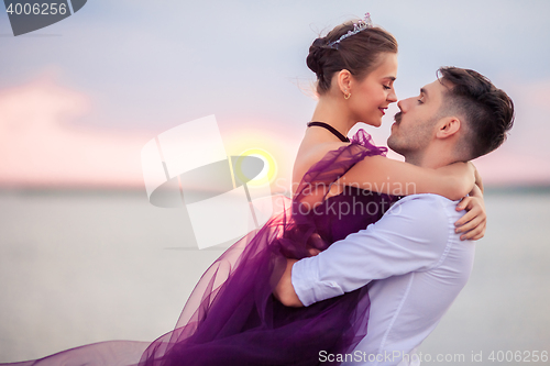 Image of Young romantic couple relaxing on the beach watching the sunset