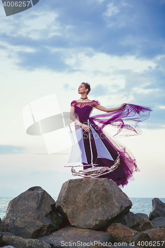 Image of Young romantic woman posing on the beach watching the sunset