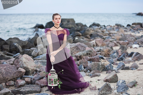 Image of Young romantic woman posing on the beach watching the sunset
