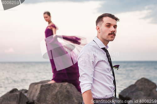 Image of Young romantic couple relaxing on the beach watching the sunset
