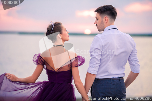 Image of Young romantic couple relaxing on the beach watching the sunset